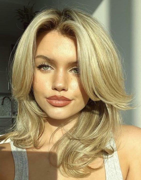 Golden layered blowout haircut with sweeping front pieces