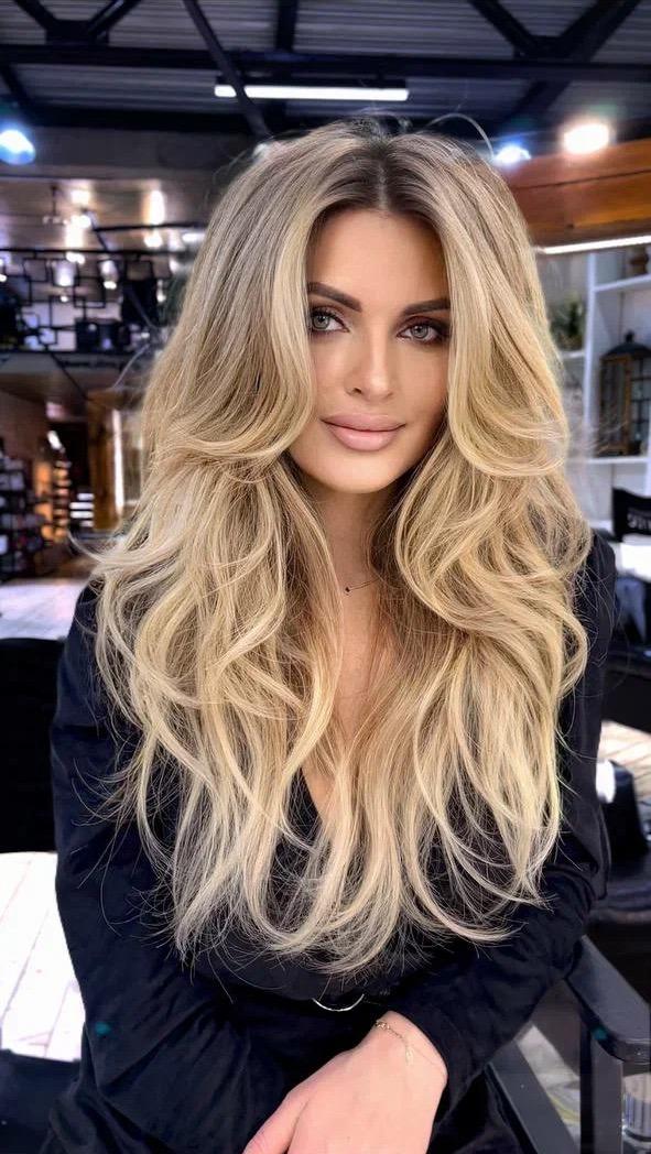 Long blonde layered blowout haircut with glamorous movement