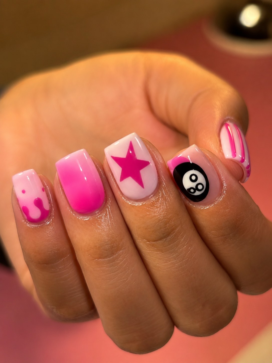 Bubblegum pink ombre nails with graphic star and eight-ball accent designs on medium square nails.