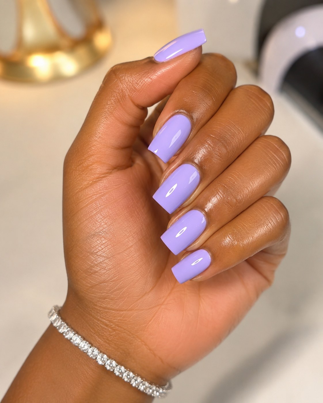 Neon lilac coffin-shaped nails with a glossy creamy finish on a deep skin tone hand.