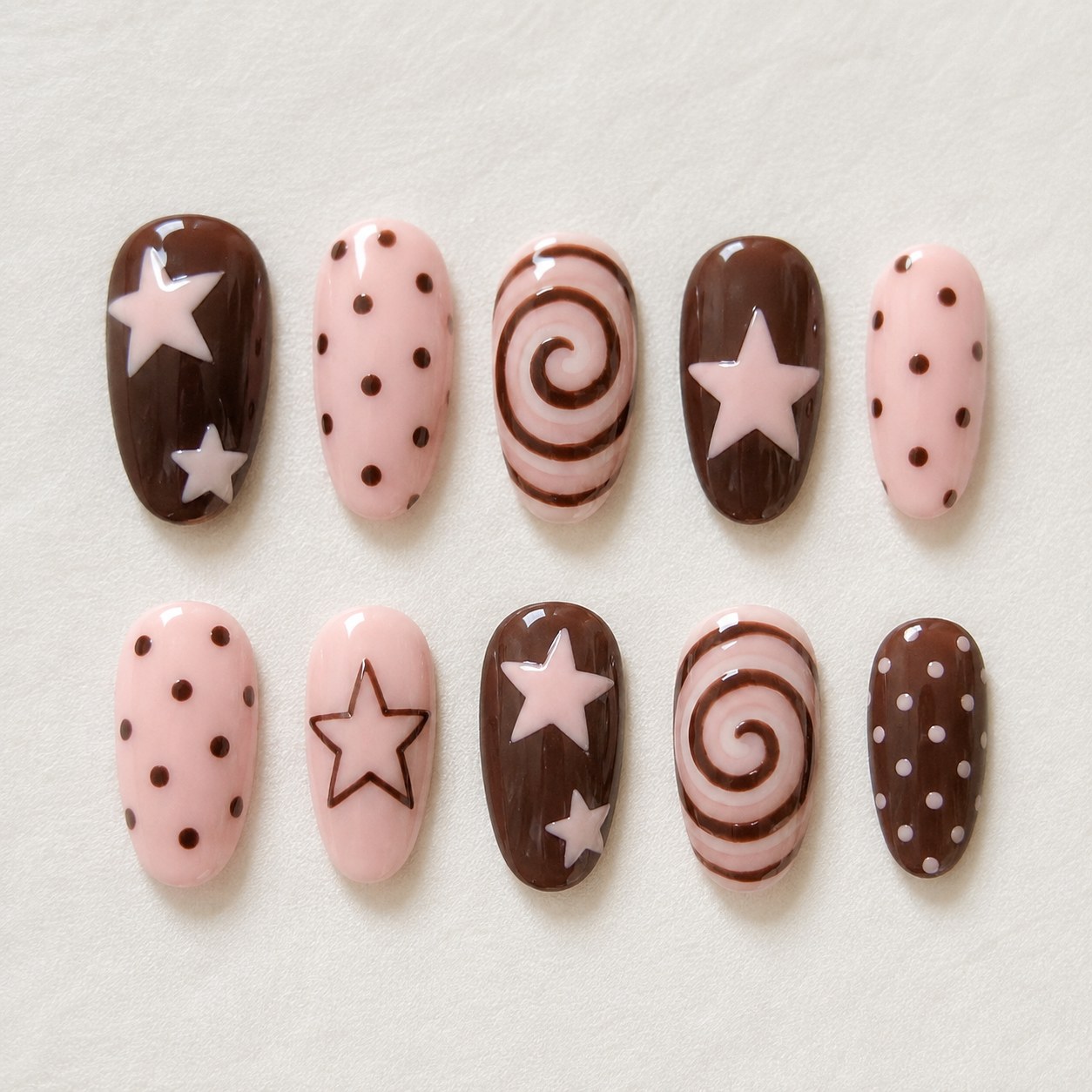 Chocolate and pink polka dot nail art paired with stars and swirl details