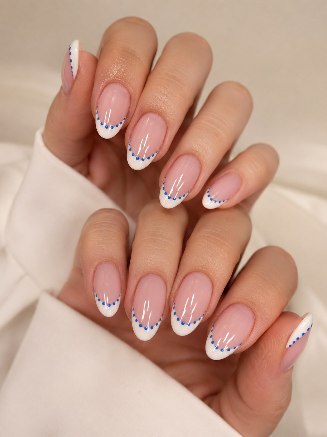 Short summer nails with a white french tip, blue dot accents, and fine line detailing near the cuticle